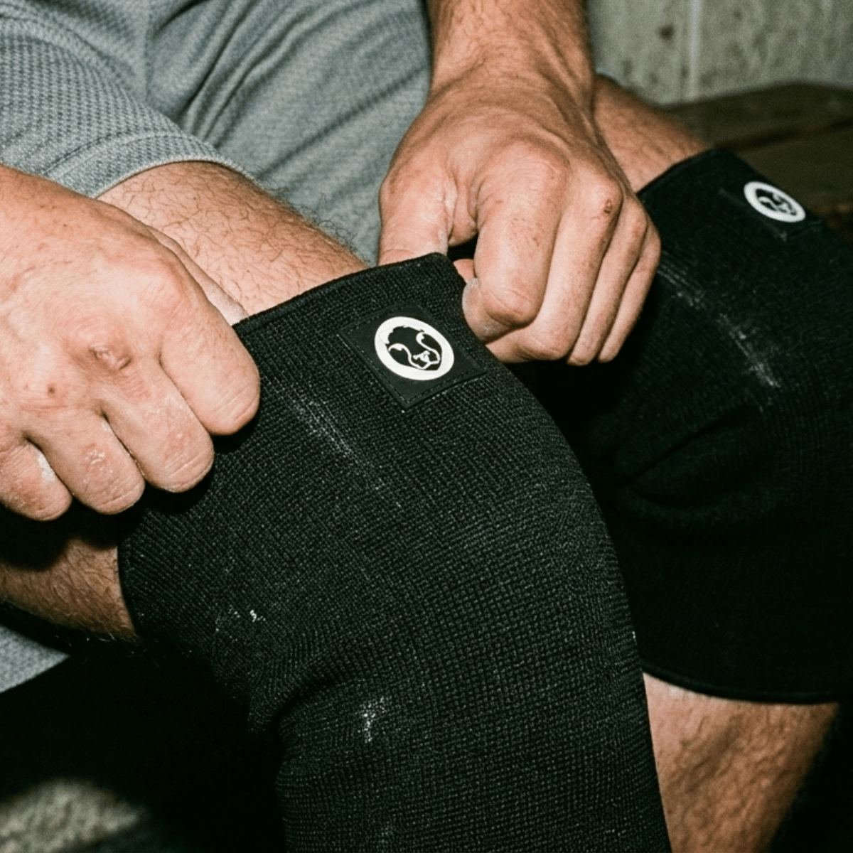 Athlete putting on Mammal Strength 3mm double ply knee sleeves for gym training and knee support